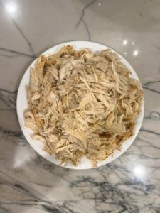 Making bulk cooked, shredded chicken is a lifesaver for family dinner later. Shred on plate using two forks.